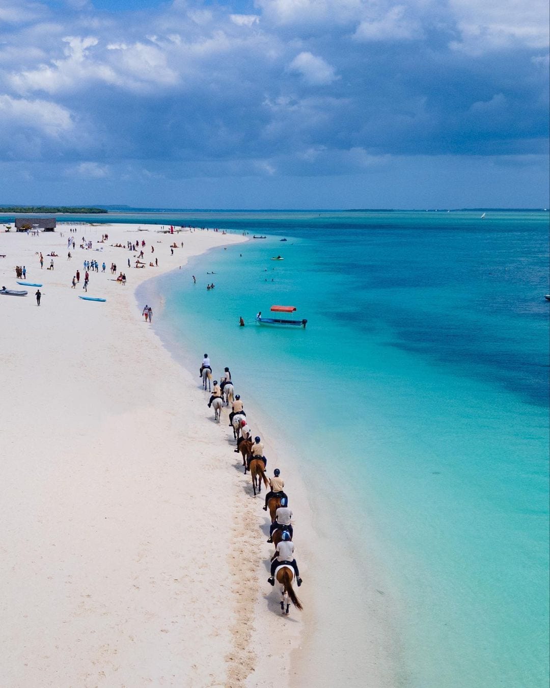 Line of riders on horseback along a white sandbank in Zanzibar