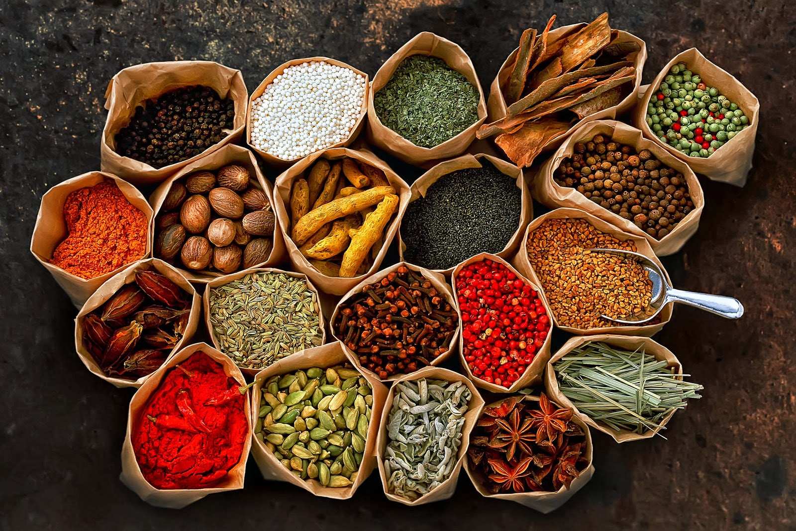 Overhead view of bags filled with colourful Zanzibar spices including cloves, cinnamon, and star anise