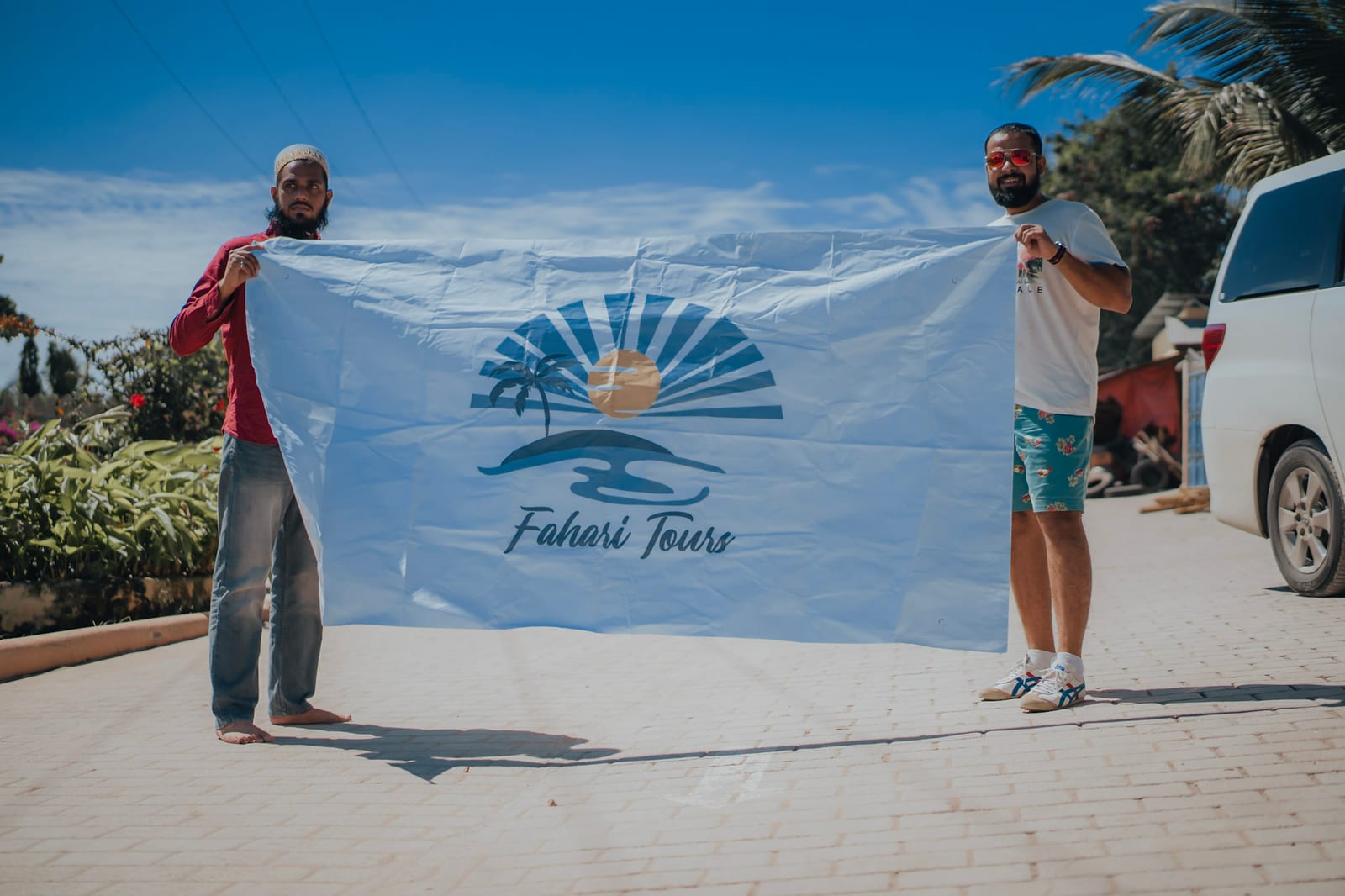 Two Fahari Tours team members holding the company flag